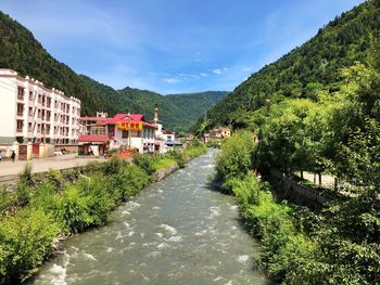 Scenic view of buildings by mountains against sky