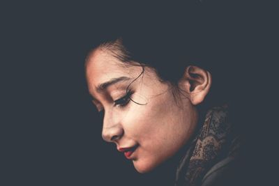 Close-up of young woman against black background