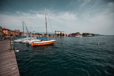 Sailboats moored on sea against sky