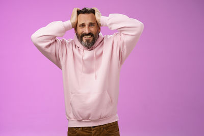 Stressed man with head in hands against purple background