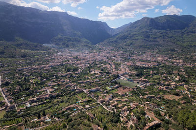 Aerial view of agricultural field by buildings against sky