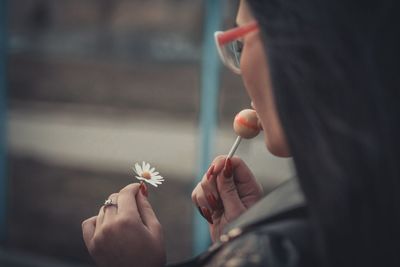 Close-up of woman eating lollipop while holding flower