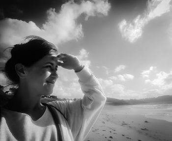 Young woman shielding eyes at beach on sunny day