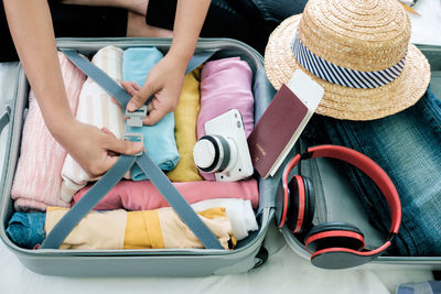 Midsection of woman packing suitcase on bed