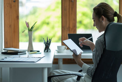 Woman using laptop while sitting on table
