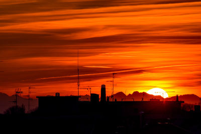 Silhouette buildings against orange sky