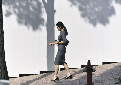 Full length of businesswoman walking against wall
