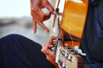 Midsection of man playing guitar