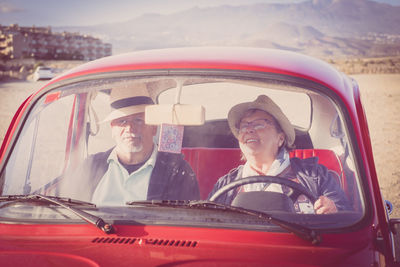 Couple sitting in red vintage car