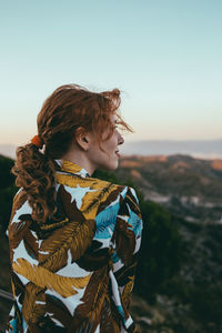 Side view of woman standing against sky during sunset