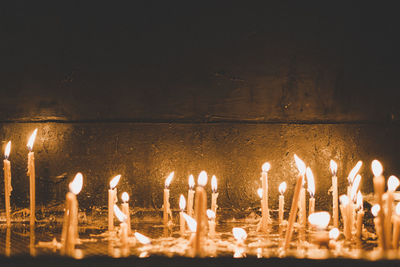 Lit candles against wall at night