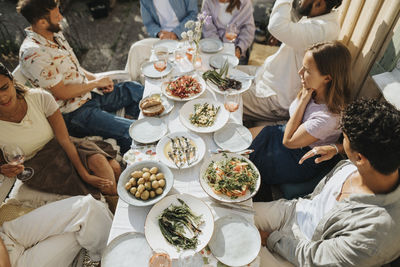 High angle view of male and female friends enjoying food during dinner party at cafe