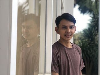 Portrait of young man standing by window