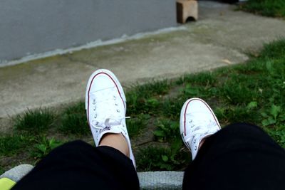 Low section of person wearing white shoes on land