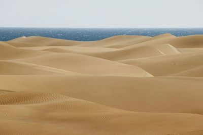 Scenic view of desert and sea against clear sky
