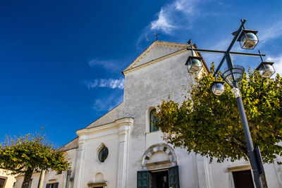 Low angle view of building and trees against blue sky