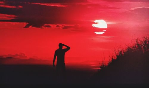Silhouette man standing against red sky during sunset