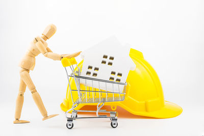 Close-up of figurine and shopping cart on white background