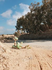 Abandoned fallen tricycle on roadside against sky