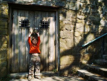 Portrait of boy standing against closed old wooden door