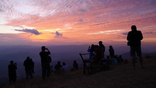 Silhouette people standing against sky during sunset