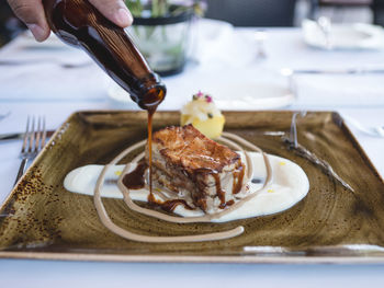 Cropped hand pouring sauce on dessert