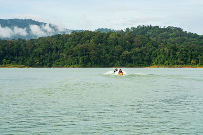 People on boat in river against sky