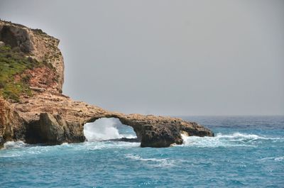 Rocks in sea against clear sky