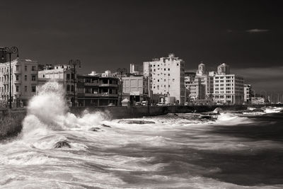 Sea by buildings against sky in city
