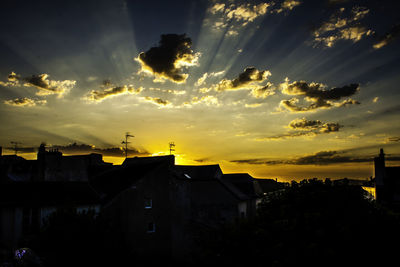 Silhouette houses and trees against sky at sunset