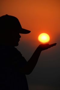 Silhouette woman standing against orange sky