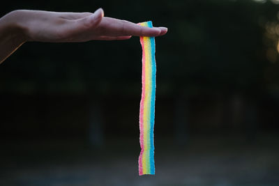 Cropped hand holding rainbow colored candy strip