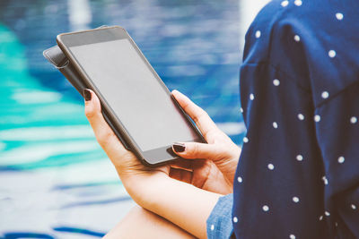 Midsection of woman using mobile phone in sea