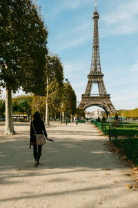 Rear view of woman walking against eiffel tower at park