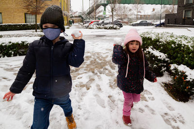 Full length of two children with snowballs in winter