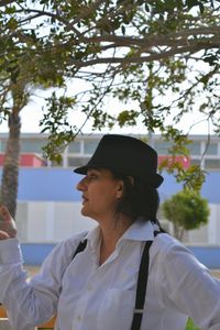 Woman wearing suspenders standing below tree