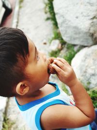 Close-up of boy eating food while standing on rock