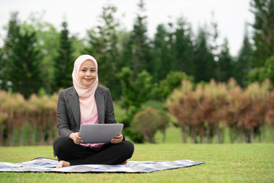 Portrait of a smiling young woman sitting on grass