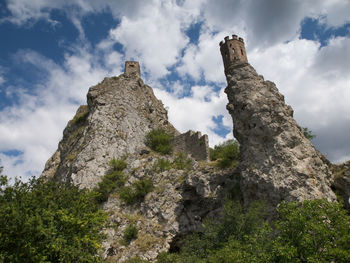 Low angle view of rock formation and castle against sky