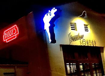 Low angle view of illuminated sign on wall in city at night