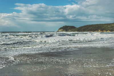 Scenic view of beach against cloudy sky