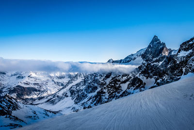 Snow covered mountain against blue sky