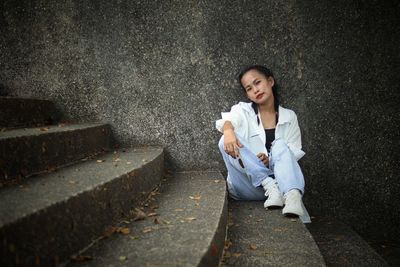 Portrait of young woman standing against wall