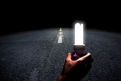 Person holding illuminated light on road