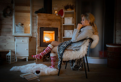 Toned photo of woman at fireplace during winter
