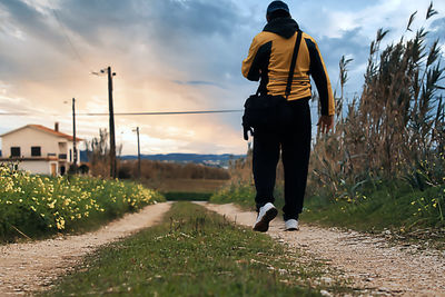 Rear view of man standing on field against sky