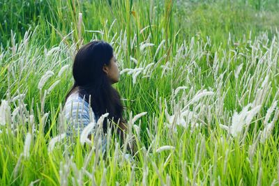 Woman sitting amidst crops on field