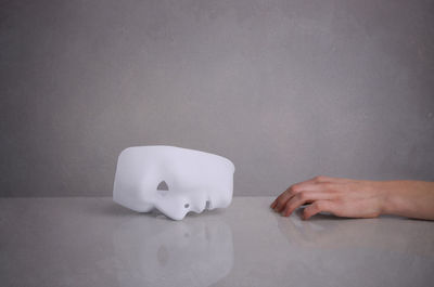 Close-up of hand on table against wall