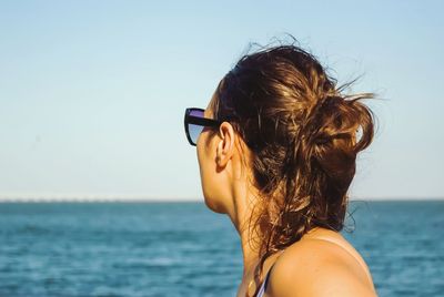 Portrait of young woman at beach against sky