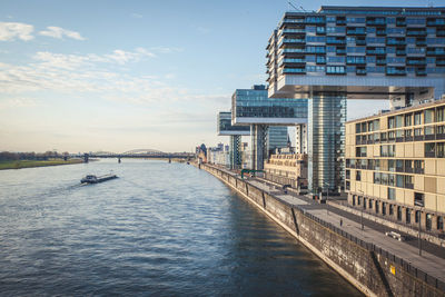 Bridge over river by buildings against sky